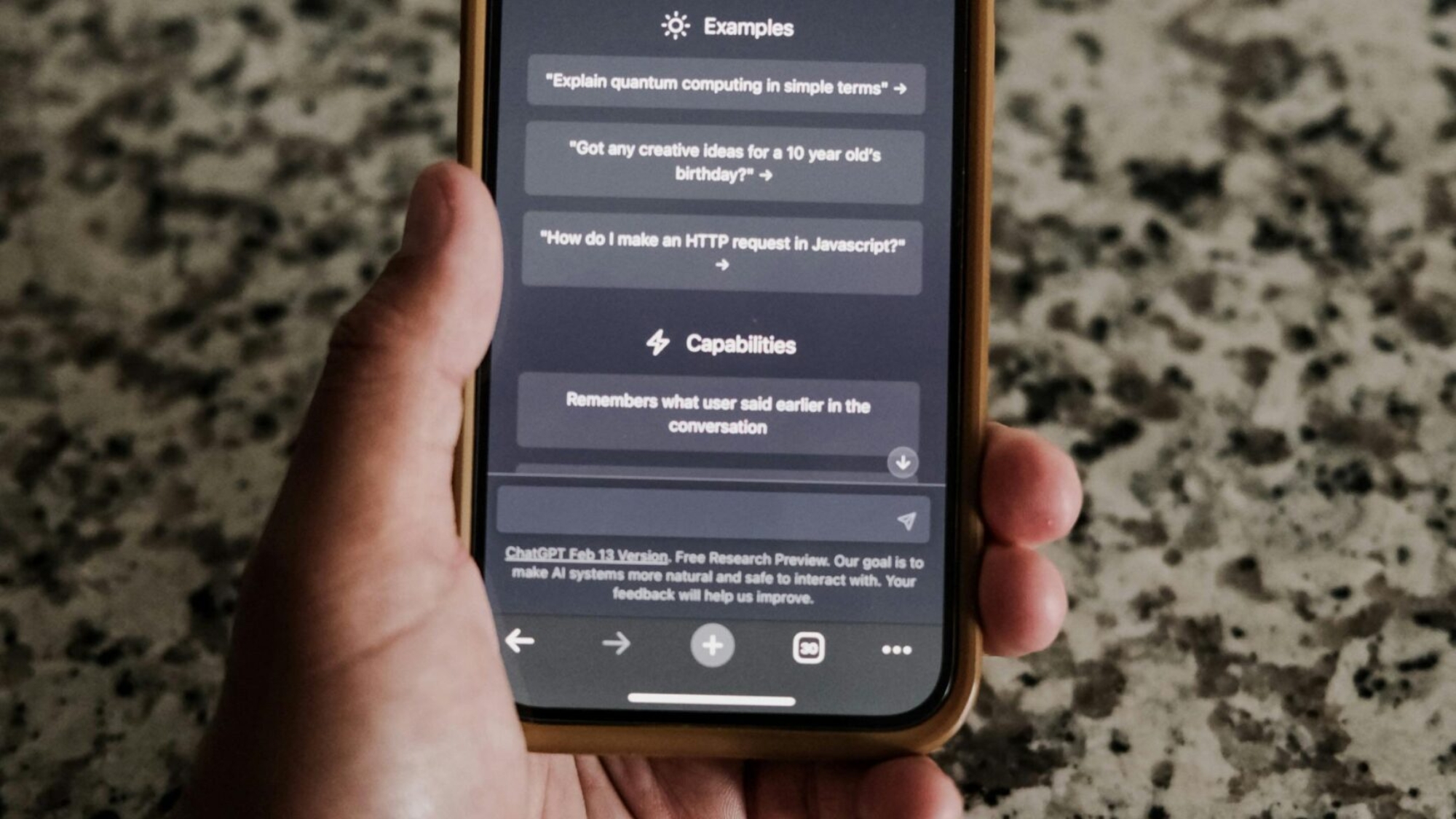A close-up of a hand holding a smartphone with ChatGPT interface on display.